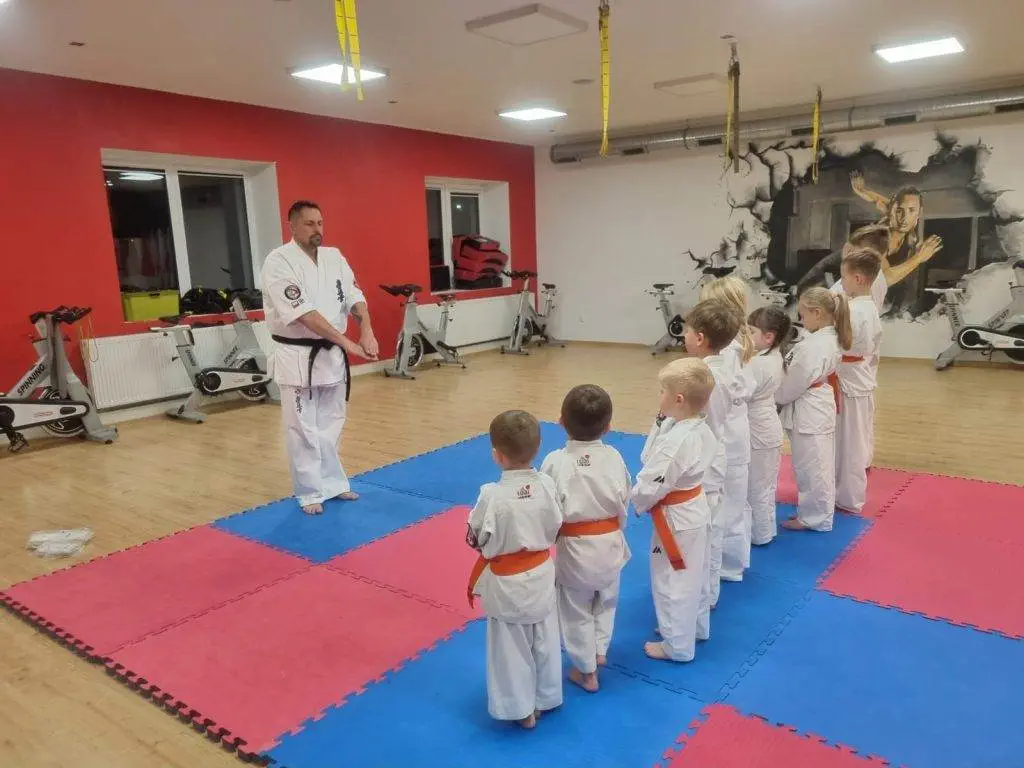Zdjęcie WhatsApp 2024-11-08 o 11.08.10_b3fd7eec Instruktor karate prowadzi trening z dziećmi w dojo.