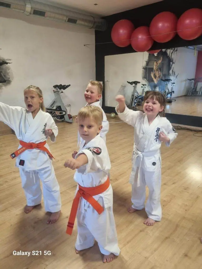 Zdjęcie WhatsApp 2024-11-08 o 11.11.42_9422cbb1 Dzieci w dojo ćwiczą karate w białych strojach.